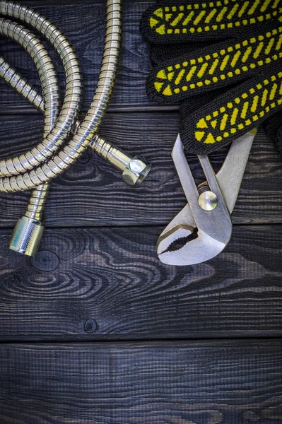 Plumbing tools for connecting water hoses on a black wooden background.