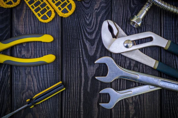 Utensili idraulici per collegare tubi dell'acqua su uno sfondo di legno nero . — Foto Stock