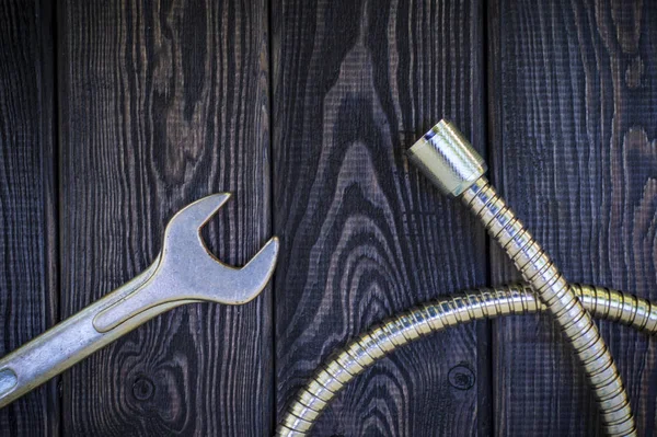 Plumbing tools for connecting water hoses on a black wooden background.