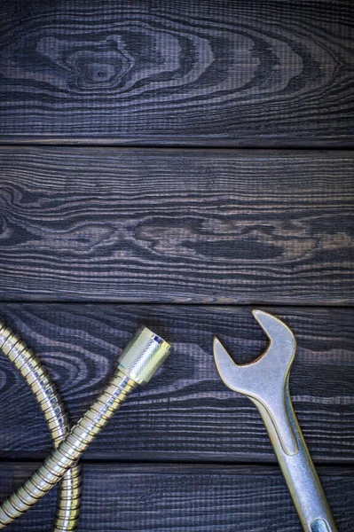 Plumbing tools for connecting water hoses on a black wooden background.