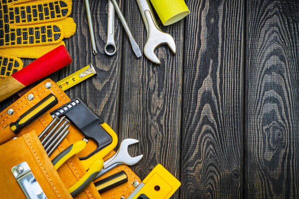Tools in the bag for carpentry and accessories on a wooden black vintage background.