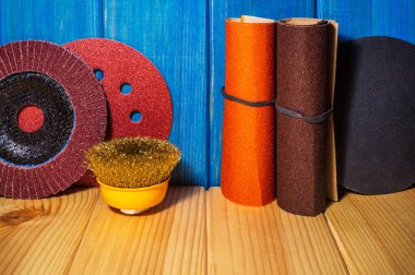 Mavi ahşap arka plan üzerinde aşındırıcı araçlar ve zımpara kağıdı seti.