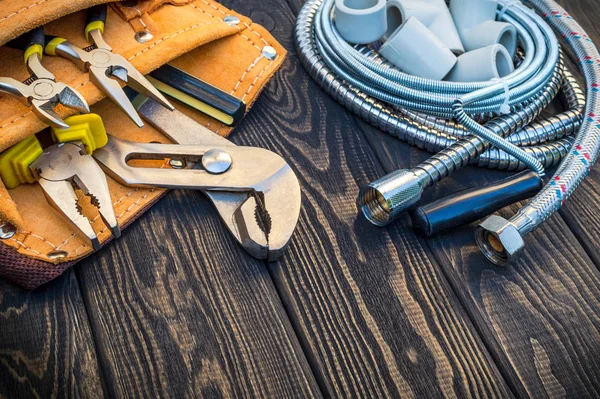 Necessary set of tools in the bag for plumbers on black vintage wooden background — Stock Photo, Image