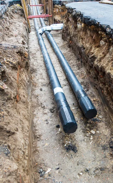 Dos tuberías de agua en zanja de pozo subterráneo durante la plomería en construcción reparación — Foto de Stock