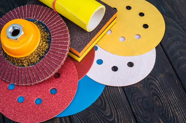 Set of abrasive tools and sandpaper on black vintage wooden background.