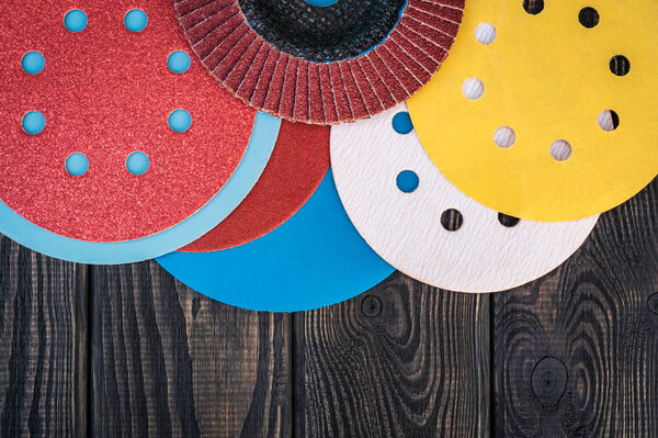 Set of abrasive tools and sandpaper different colors on black vintage wooden background