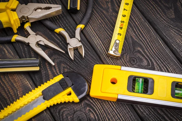 Herramientas para maestro constructor y accesorios sobre un fondo vintage negro de madera — Foto de Stock