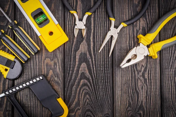 Herramientas para maestro constructor y accesorios sobre un fondo vintage negro de madera —  Fotos de Stock