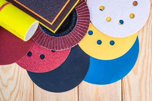 Set de herramientas abrasivas y papel de lija de diferentes colores sobre fondo de madera —  Fotos de Stock