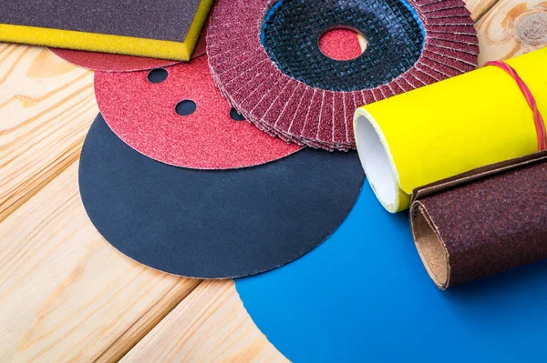 Set de herramientas abrasivas y papel de lija de diferentes colores sobre fondo de madera — Foto de Stock
