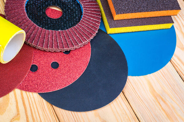 Set of abrasive tools and sandpaper different colors on wooden background