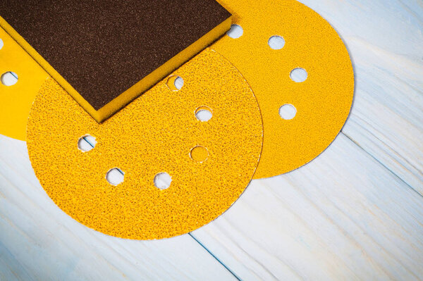 Set of yellow abrasive tools and sandpaper on wooden blue boards