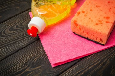 Koyu renkli ahşap tahtalarda temizlik için ped ve havlu ile sıvı deterjan.