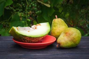 Olgun armutlar ve karpuzlar masada dilimler, meyve hala hayattadır.