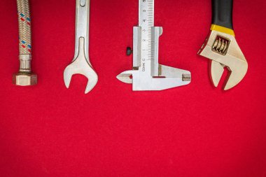 Kırmızı arka planda tesisatçılar için alet ve hortum seti ve reklam için yer var.