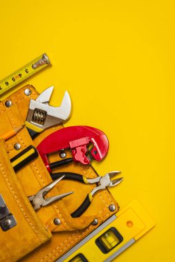 Tesisatçı usta elektrikçi tarafından onarım ya da inşaattan önce sarı arka planda süet çantada hazırlanan alet takımı.