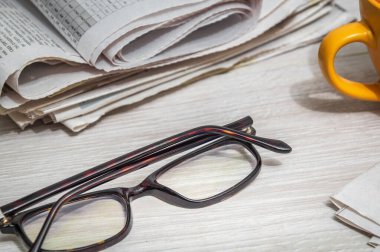 Masada gazete okumak için gözlük ve bir kupa. Planlama ve analiz sırasında ev ortamı