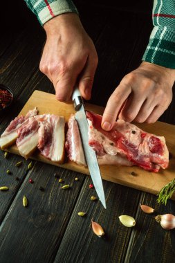 Aşçı elleri akşam yemeği için hazırlamadan önce domuz yağı ya da domuz eti kesmek için bir bıçak kullanır. Sağlıklı ve yağlı bir yemek hazırlama konsepti.