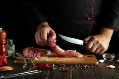 Bir kasap rosto hazırlamak için dana etini bıçakla keser. Salon mutfağında et yemeği pişirmek gibi basit bir kavram..