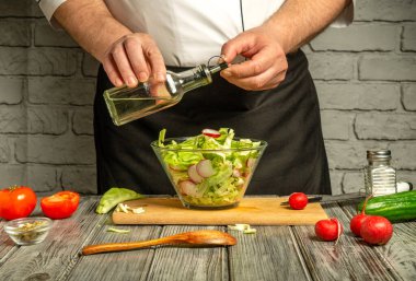 Bir şef taze sebze, sebze, turp, domates ve salatalıkları ahşap bir masaya serpiştirir..