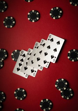 Aynı takımdan beş iskambil kartı, kırmızı arkaplanda siyah poker fişleri ile çevrili olarak sergilenmektedir. Bu kurgu, arkadaşlarla bir kumarhane oyununun heyecanını yansıtıyor..