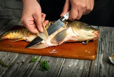 Eller ustalıkla fileto yapıyor. Tahtada taze bir balık var. Gündüz sıcak bir mutfak ortamında geleneksel bir yemek yapma tekniğini sergiliyor..