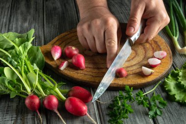 Taze yeşillik ve otlarla çevrili tahta bir tahtanın üzerinde turpları ustalıkla doğrayarak. Bu sahne sağlıklı yemek pişirmenin ve yemek hazırlamanın özünü yansıtıyor..