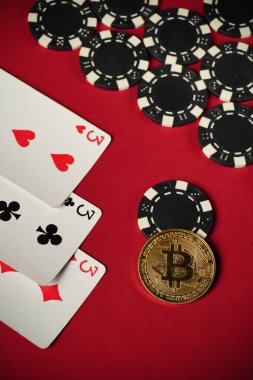 Kırmızı keçeli masa, üç çeşit oyun kartı ve siyah-beyaz poker fişleri ile parlayan altın Bitcoin 'in arka planına karşı heyecan verici bir kumarhane oyunu sırasında.