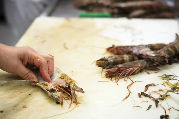 Cooks are cleaning tiger shrimps in the restaurant\'s kitchen