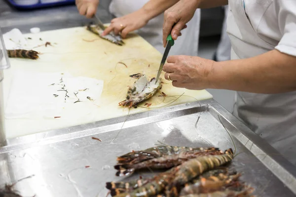 Cooks are cleaning tiger shrimps in the restaurant's kitchen