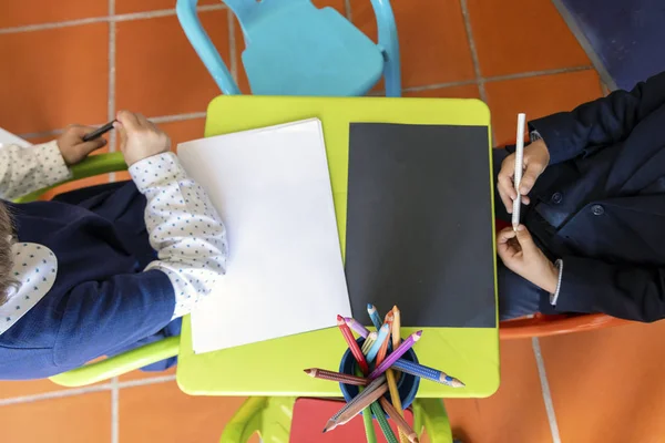 Two kids sitting by small table ready to draw — Stock Photo, Image