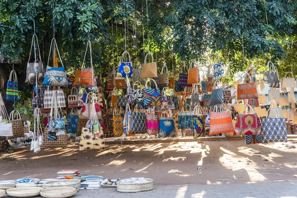 Mercado africano tradicional vendendo sacos coloridos pendurados na árvore — Fotografia de Stock