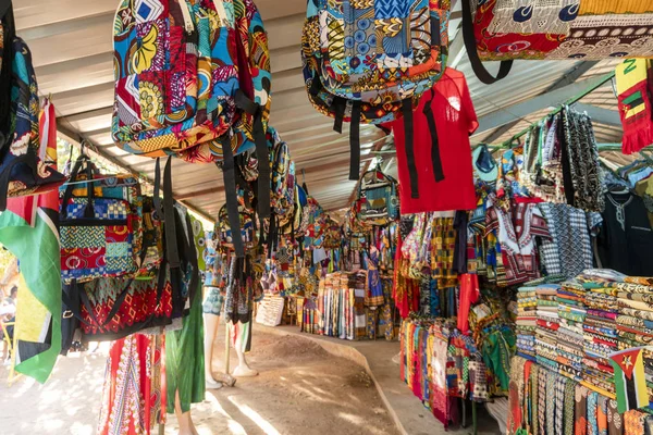 Mercado africano tradicional que vende mochilas coloridas, ropa — Foto de Stock