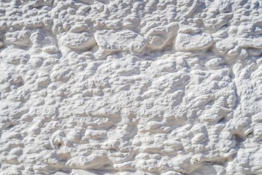 Düzensiz eski taşlar ve alçı beyaza boyanmış.