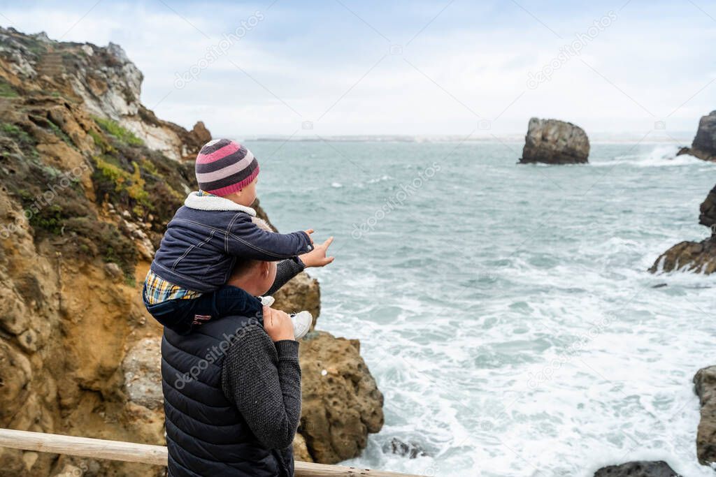 Father and little son admiring beautiful Papoa islet in Peniche, Leiria district, Portugal