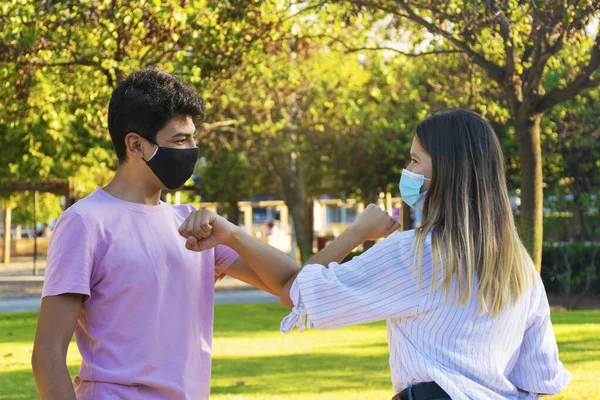 Kız ve erkek dışarıda dirseklerle selamlaşıyor. Maskeli arkadaşlar artık normal. Sosyal uzaklık.