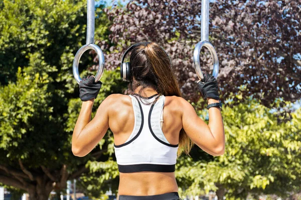 Kulaklıklı ve maskeli atletik genç bir kadın spor salonunda egzersiz yapıyor.