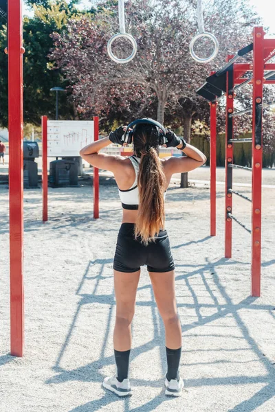 Fitness kızı kulaklıklarını jimnastik parkına yerleştiriyor.