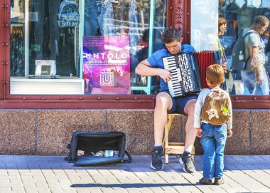 Kiev, Ukrayna - Eylül, 22, 2018: Küçük çocuk Khreshchatyk'a bir sokak müzisyeni akordeon üzerine oynayarak hayran.