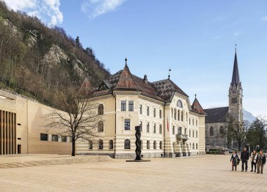 Vaduz, Lihtenştayn - 06 Nisan 2019: Eski Lihtenştayn Parlamento binası ve gün batımında Saint Florin Katedrali kulesi.