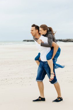 Sahilde sırtında bir kız taşıyan bir adam.