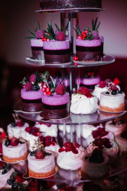 Mor ve pembe cupcake standı. Çilek ve yapraklarla dekore edilmiş. 