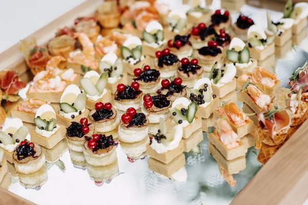 Different canapes with salmon, cucumber, berries and eggs served on a table