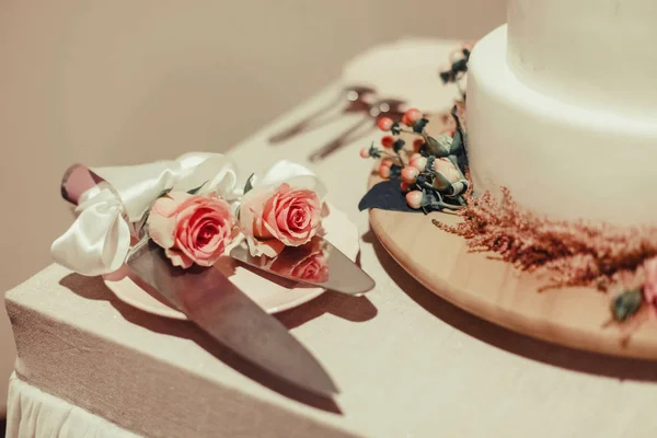 ピンクのバラで飾られた白いウェディングケーキ ナイフ フォークへら — ストック写真