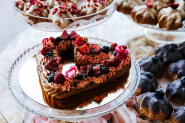 Çilek ile süslenmiş kalp şeklinde Kek, bir ziyafet masasında servis.