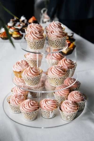 Pink cupcake stand on the white banquet table.