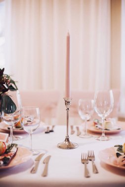 Pembe mum ile pembe tonlarda romantik masa ayarı.
