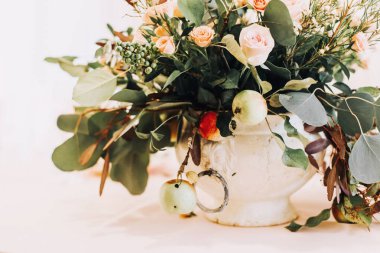 Rustik bir tencerede pembe gül çiçekleri ve elma ağacı dalları ile romantik masa ayarı.