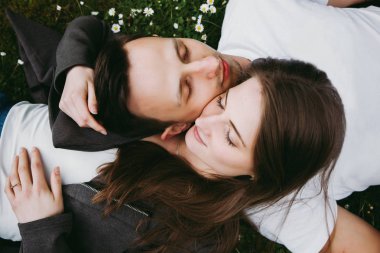 Genç sevgi dolu çift açık havada çimenler üzerinde yatan, gözleri kapalı, yukarıdan aşağıya görünümü. 