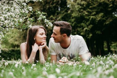 Genç sevgi dolu çift açık havada çimenler üzerinde yatarken, sarılma.